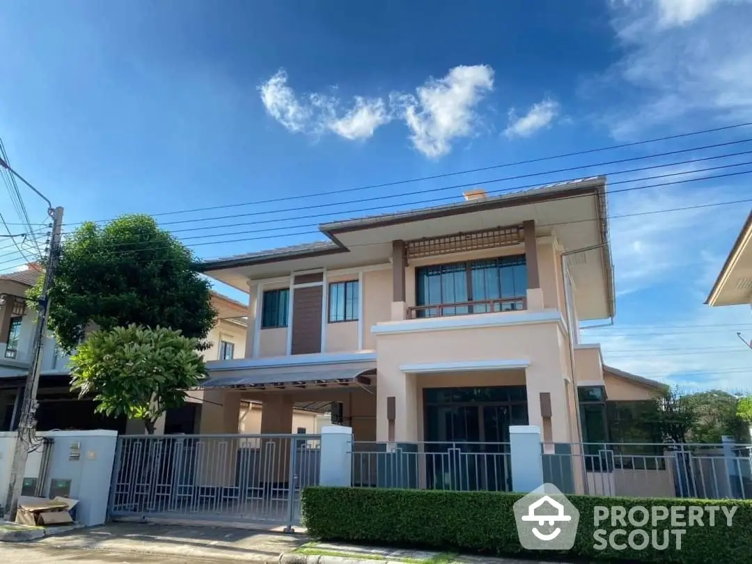 Elegant two-story residence with a spacious balcony and modern design, nestled under a clear blue sky with lush surroundings.