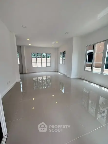 Spacious empty living room with glossy tiled floors and large windows.