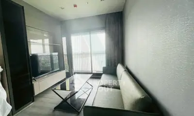 Modern living room with sleek furniture and large window offering natural light and balcony access.