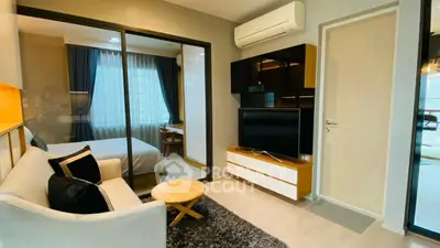 Modern living room with cozy seating and bedroom view in stylish apartment