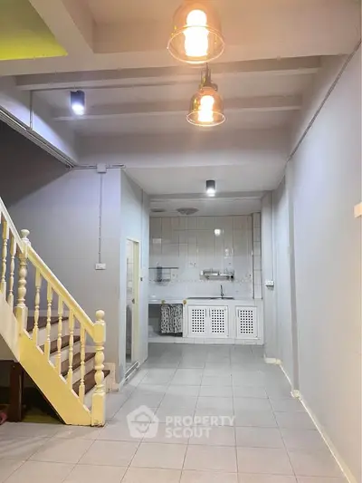 Spacious open-plan kitchen with staircase and modern lighting fixtures.