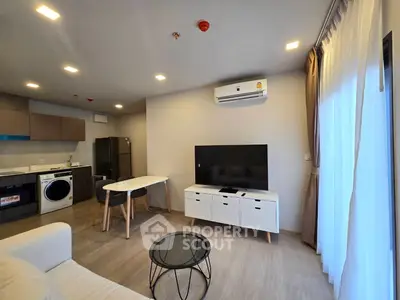 Modern living room with open kitchen, featuring sleek furniture and appliances, perfect for urban living.