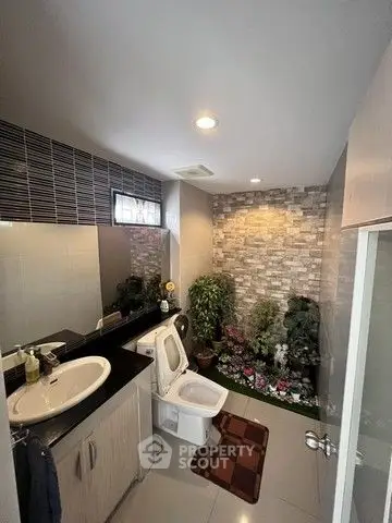 Modern bathroom with stylish decor and indoor plants enhancing the ambiance.