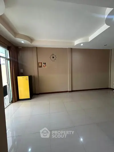 Spacious empty living room with modern ceiling design and large windows.