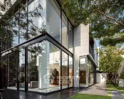 Modern luxury home exterior with large glass windows and lush greenery