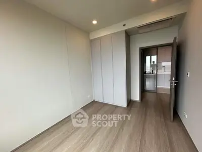 Spacious modern bedroom with sleek wooden flooring and built-in closet