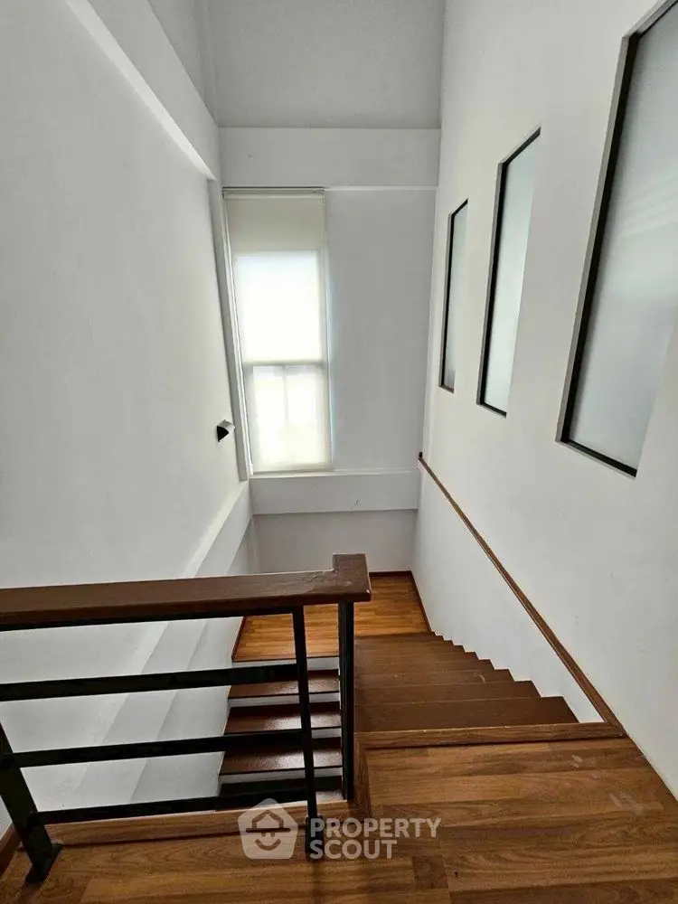Modern staircase with wooden steps and sleek railing in a bright home interior