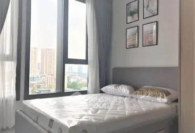 Modern bedroom with large window and city view, featuring stylish decor and comfortable bedding.