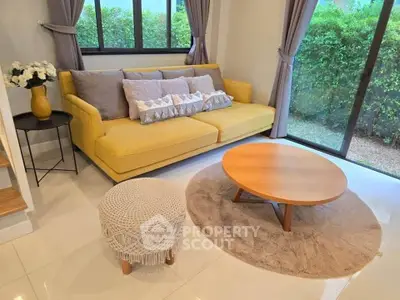 Charming living room with yellow sofa, round wooden table, and garden view.