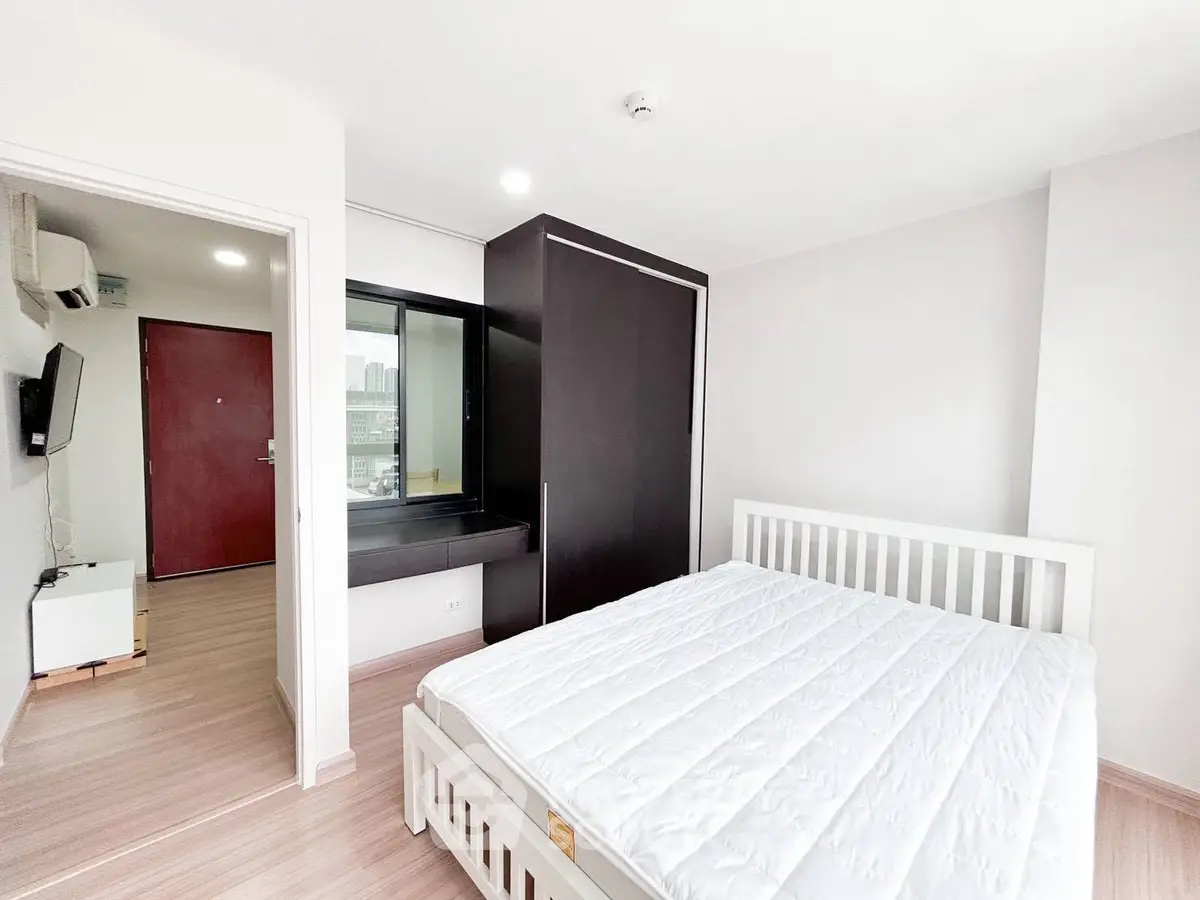 Modern bedroom with white bed frame and large wardrobe in a bright apartment