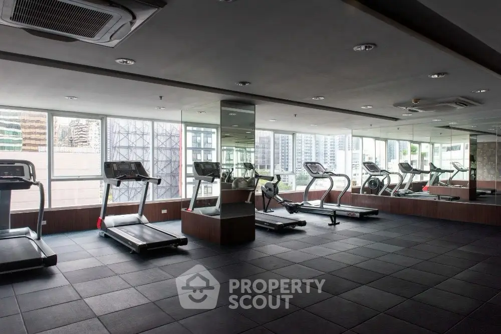 Modern gym with treadmills and city view, perfect for fitness enthusiasts in urban living spaces.