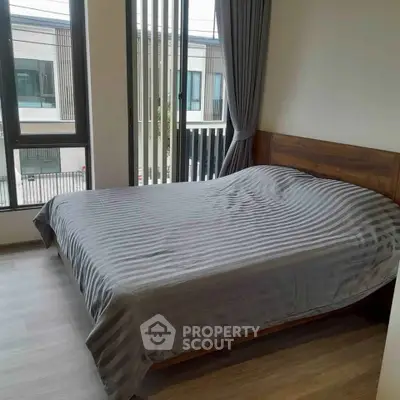 Modern bedroom with large windows and stylish decor in a contemporary apartment.