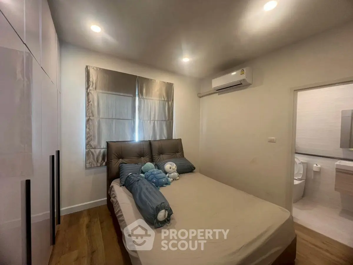 Cozy bedroom with modern decor and ensuite bathroom, featuring soft lighting and air conditioning.