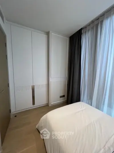 Modern bedroom with sleek wardrobe and large window with curtains