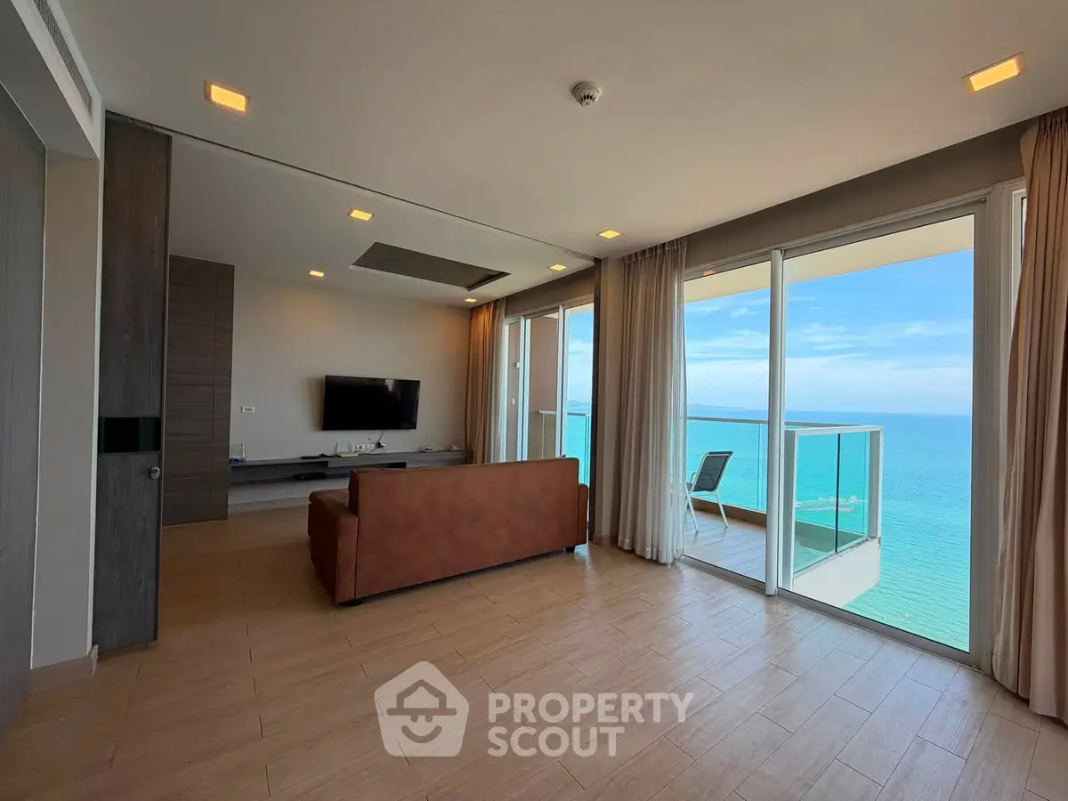 Stunning oceanfront living room with floor-to-ceiling windows and balcony access, offering breathtaking sea views.