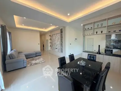 Spacious modern living and dining area with elegant lighting and sleek furniture.