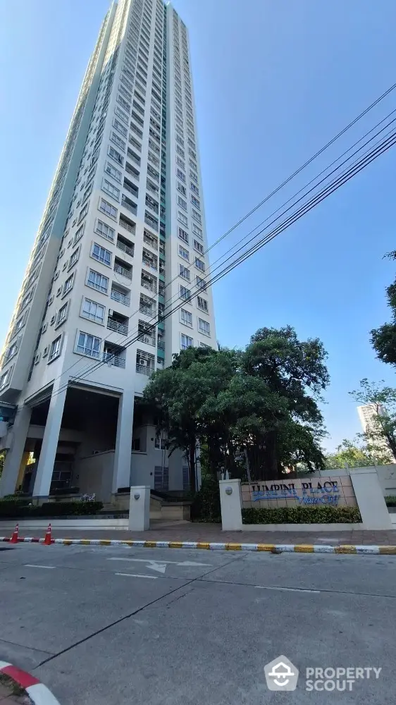 Stunning high-rise condominium building with modern architecture and lush greenery at entrance.