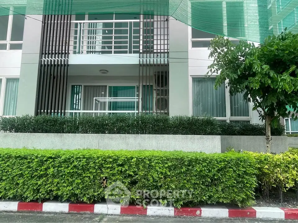 Modern apartment building exterior with lush greenery and sleek design.
