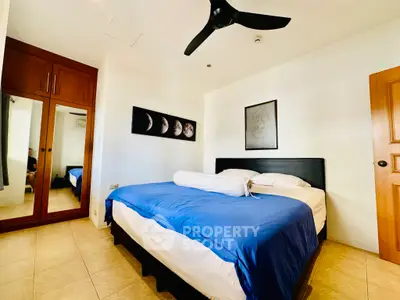 Spacious bedroom with modern decor and ceiling fan, featuring a comfortable bed and mirrored wardrobe.