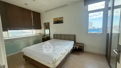 Spacious bedroom with large windows offering city views and modern furnishings.