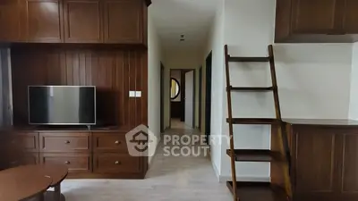 Charming living room with wooden cabinetry and modern TV setup, featuring a stylish ladder for added character.