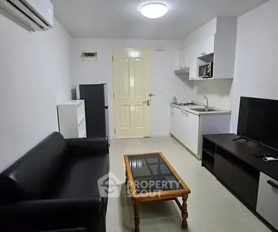 Cozy living room with modern furniture and compact kitchen area.