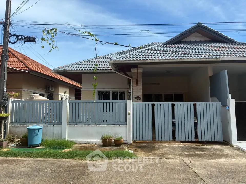 Charming single-story house with tiled roof and fenced yard in a serene neighborhood.