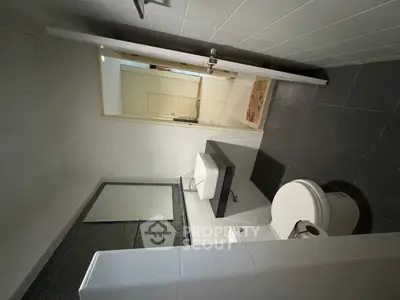 Modern bathroom with sleek fixtures and minimalist design, featuring a white sink and toilet.