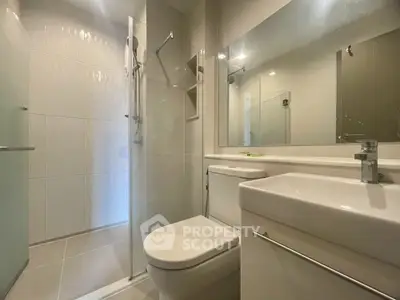Modern bathroom with glass shower and sleek fixtures in contemporary apartment.