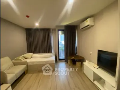 Modern studio apartment with cozy living area and balcony access, featuring sleek furniture and air conditioning.