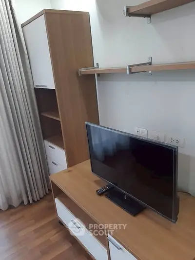 Modern living room with sleek wooden furniture and flat-screen TV, perfect for cozy relaxation.