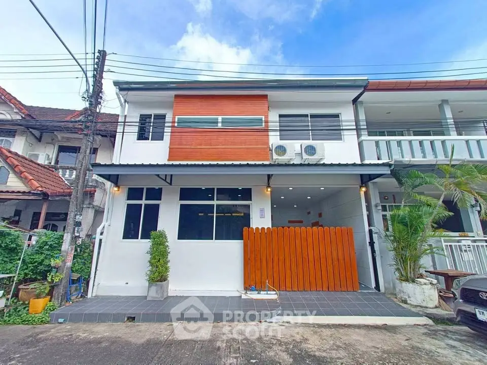 Modern two-story townhouse with sleek facade and gated entrance in a suburban neighborhood.