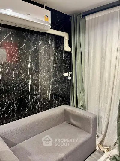 Modern living room with sleek black marble wall and gray sofa, featuring air conditioning and elegant curtains.