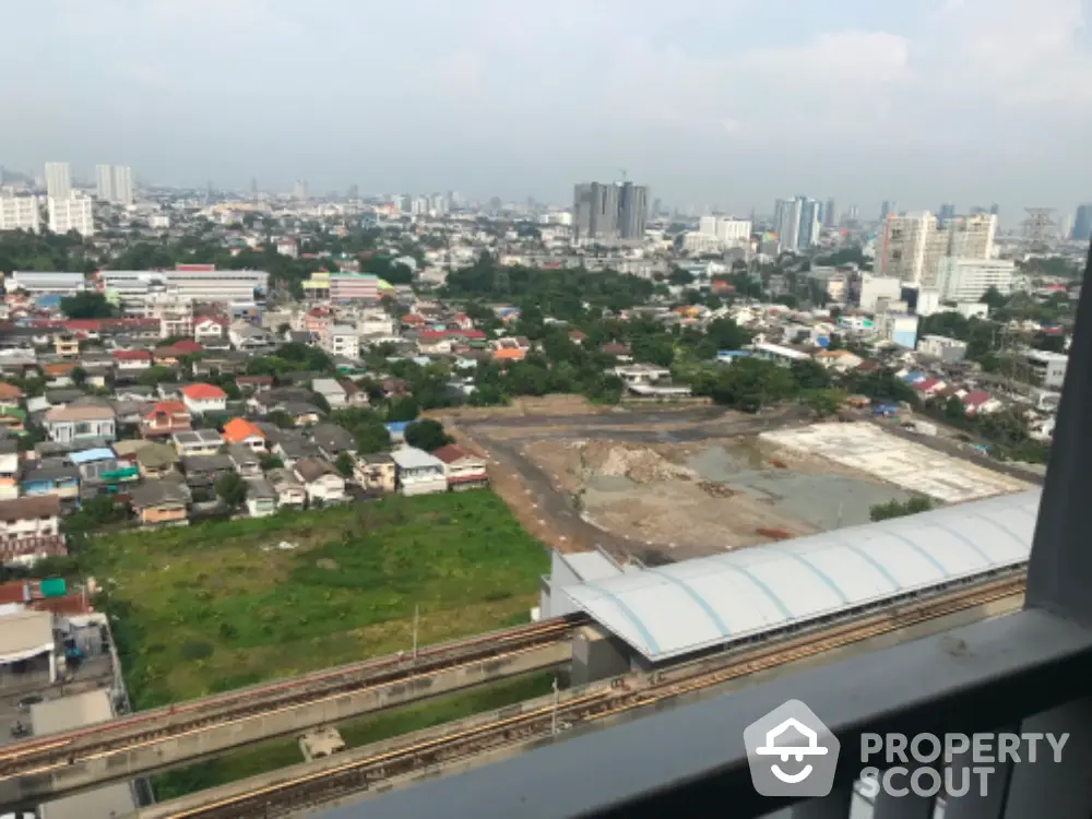 Stunning cityscape view from high-rise balcony overlooking urban landscape and railway tracks.