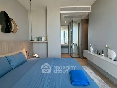 Modern bedroom with sleek design and city view, featuring blue bedding and minimalist decor.