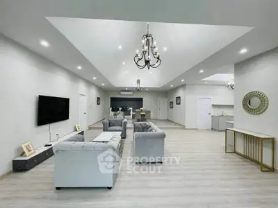 Spacious modern living room with elegant chandeliers and plush seating in open layout.