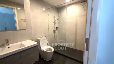 Modern bathroom with sleek design and glass shower enclosure in contemporary apartment.