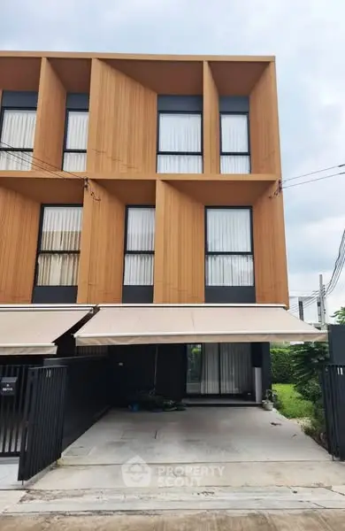Modern three-story townhouse with sleek wooden facade and spacious driveway.