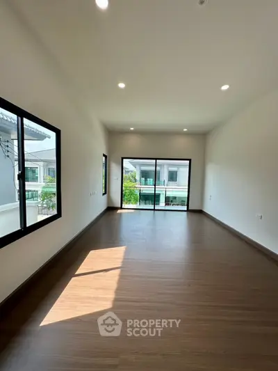 Spacious empty room with large windows and balcony view, perfect for customization.