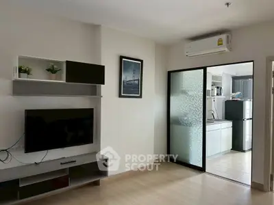 Modern living room with TV and sliding glass door to kitchen in a stylish apartment.