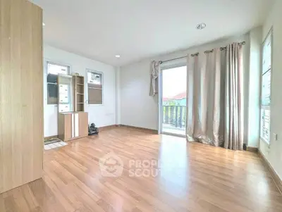 Spacious empty room with wooden flooring and balcony access, ideal for customization.
