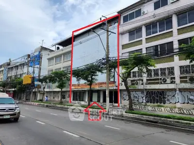 Street view of commercial building with graffiti and trees, ideal for urban development.