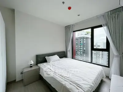 Modern bedroom with large window offering city view in high-rise apartment