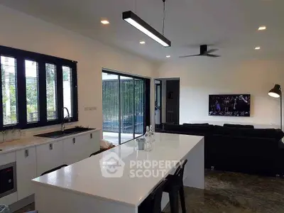 Modern open-plan kitchen and living room with sleek design and pool view.