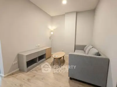Modern minimalist living room with cozy gray sofa and sleek wooden flooring.