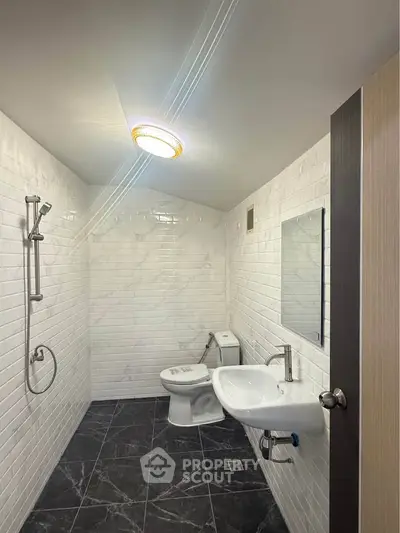 Modern minimalist bathroom with sleek white tiles and black floor.