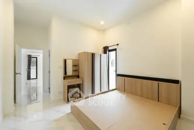 Spacious bedroom with modern wooden furniture and ample natural light.