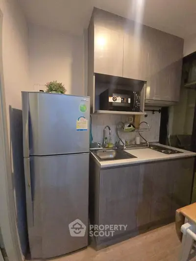 Modern compact kitchen with sleek cabinetry and stainless steel appliances in a cozy apartment.