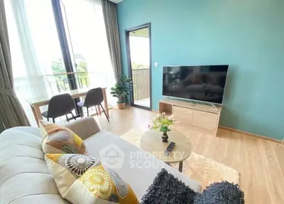 Bright modern living room with large TV, cozy sofa, and balcony view.