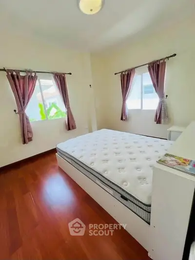 Bright and airy bedroom with hardwood floors and large windows in a modern home.